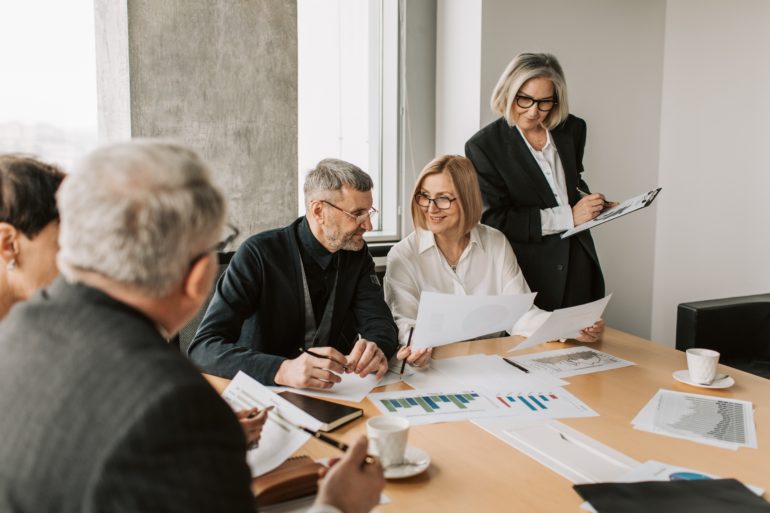 Group of mature people smiling, discussing spread sheets and data